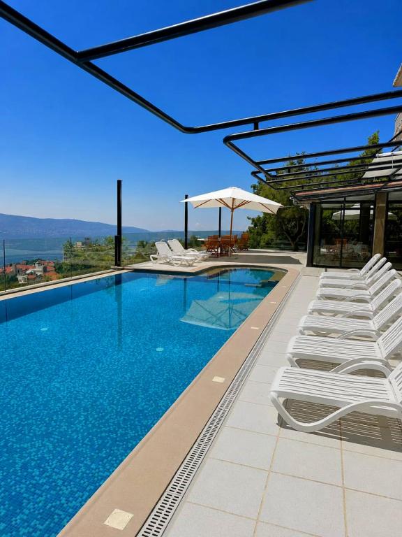 a swimming pool with white chairs and an umbrella at Oakland Hotel in Rayfūn