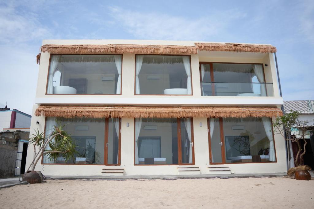 a house with large windows on the beach at Sala Beach Villa Phú Quý in Cù Lao Thu