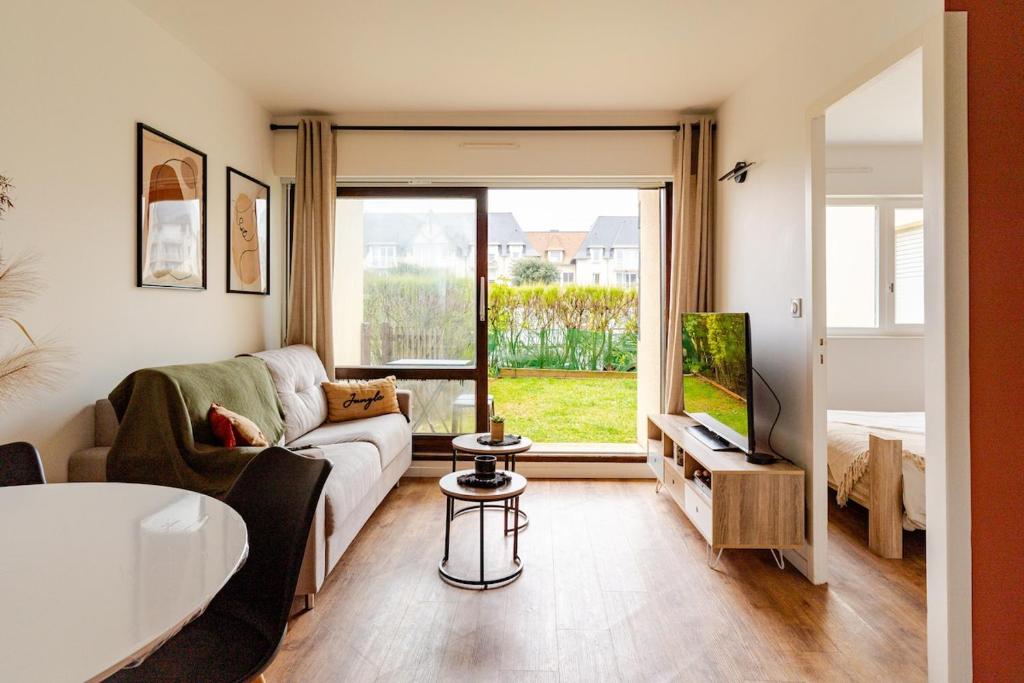 a living room with a couch and a large window at Appartement refait à neuf, 4 pers à Courseulles in Courseulles-sur-Mer