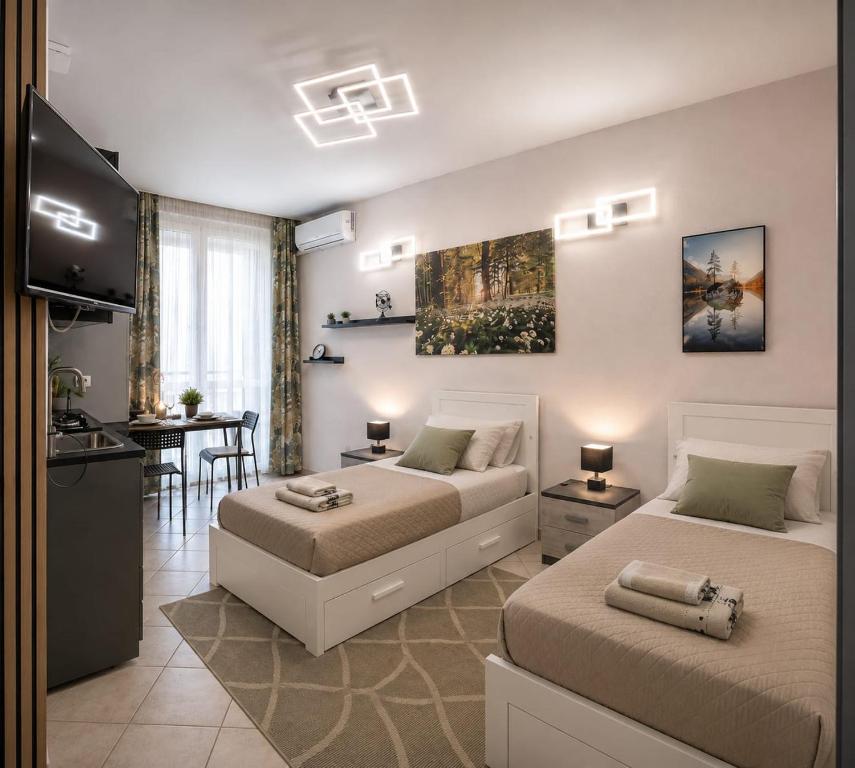 a bedroom with two beds and a kitchen and a table at Monolocale Liberty in Gorizia