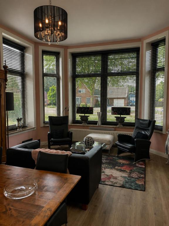 a living room with a couch and chairs and windows at Feel-Fine Guesthouse in Nieuw-Buinen