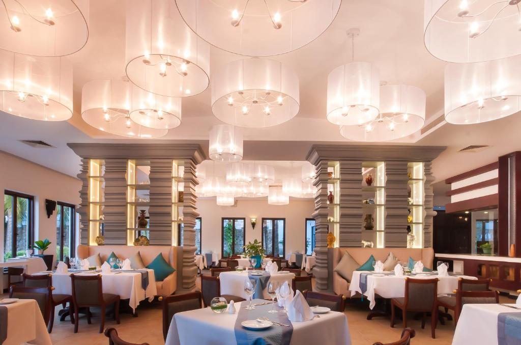 a restaurant with white tables and chairs and chandeliers at Lotus Blanc Resort in Siem Reap