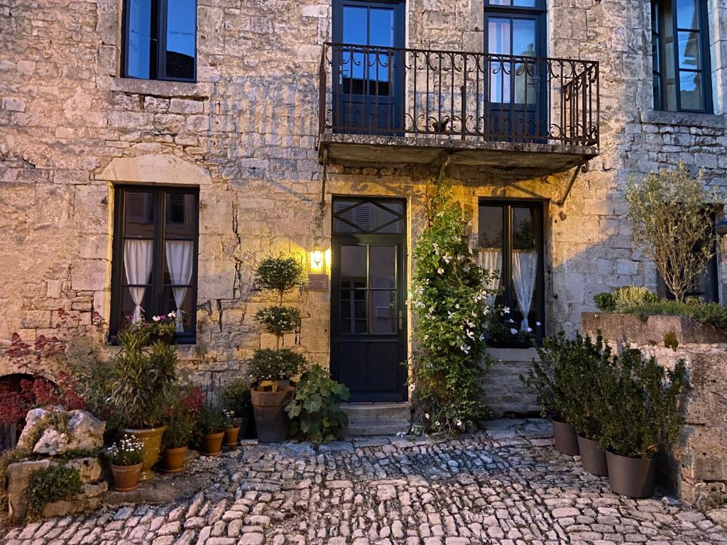 a stone house with a black door and a balcony at Maison Galimard in Flavigny-sur-Ozerain