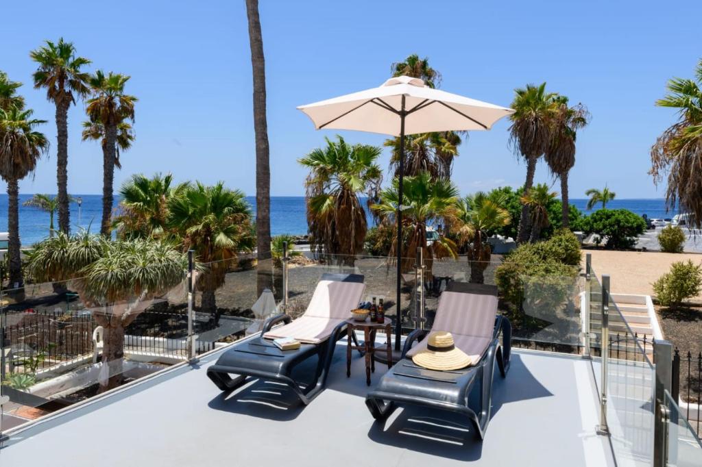 a patio with chairs and an umbrella and the beach at Casa Sherazad in Tías