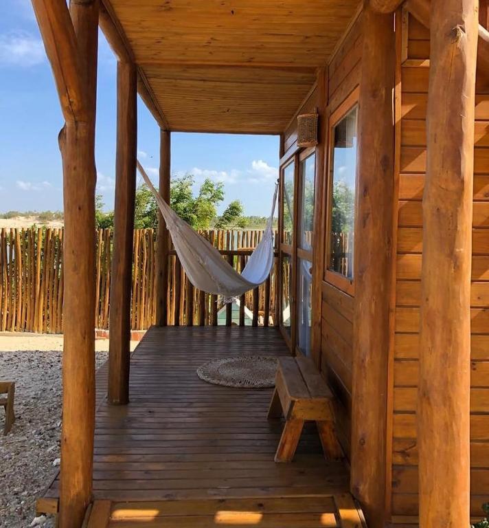 a hammock on the porch of a log cabin at Vila do Pescador in Camocim