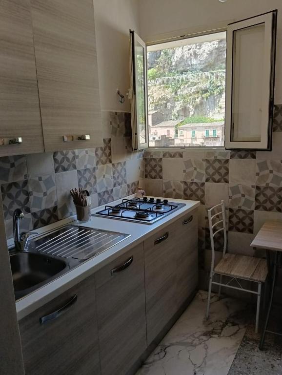 a kitchen with a stove and a sink and a window at Correri 125 in Modica
