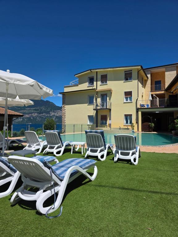 a group of lawn chairs and an umbrella and a building at Hotel Garni Rosmari in Brenzone sul Garda
