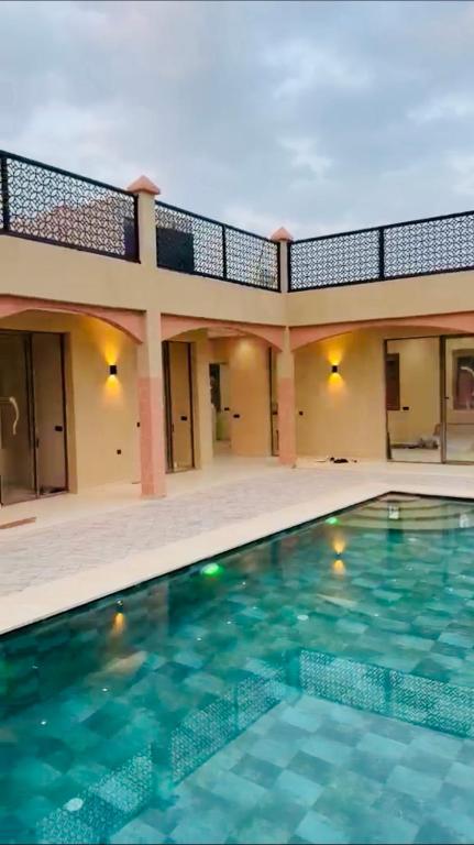 a swimming pool in front of a house at Villa Marrakech Rouge in Aït Zat