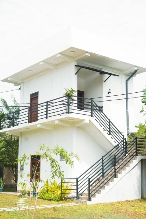 a white building with stairs and a balcony at Villa Downsouth Nilaveli in Kumpurupiddi