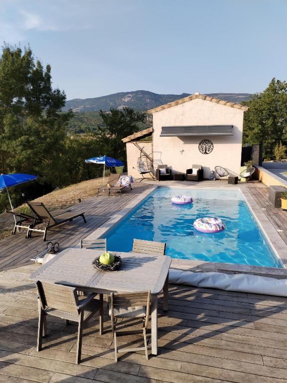 a large swimming pool with a table and chairs at Le Cigalou - Drôme Provencale in Sainte-Jalle