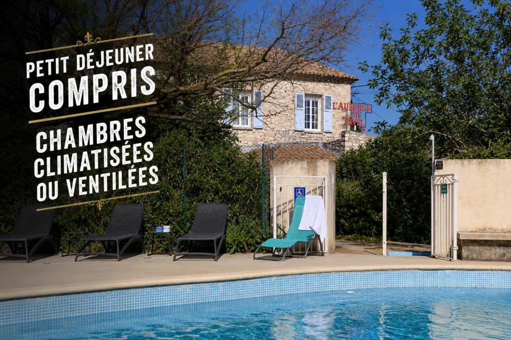 a swimming pool with chairs and a sign next to a house at Logis Auberge De Tavel in Tavel