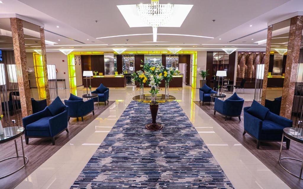 a lobby with blue chairs and a table with flowers at شير فل in Unayzah
