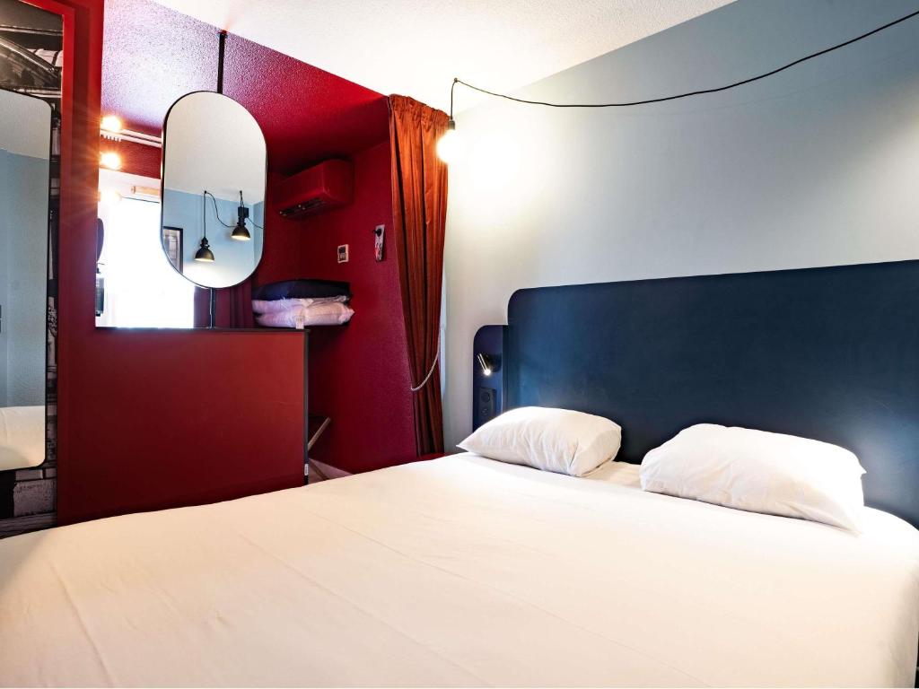 a bedroom with a white bed with a black headboard and a mirror at ibis Styles Bourg-en-Bresse Centre in Bourg-en-Bresse