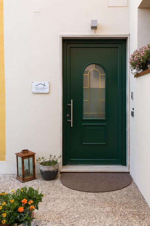 a green door on a white house with flowers at Small Guesthouse in Bussolengo