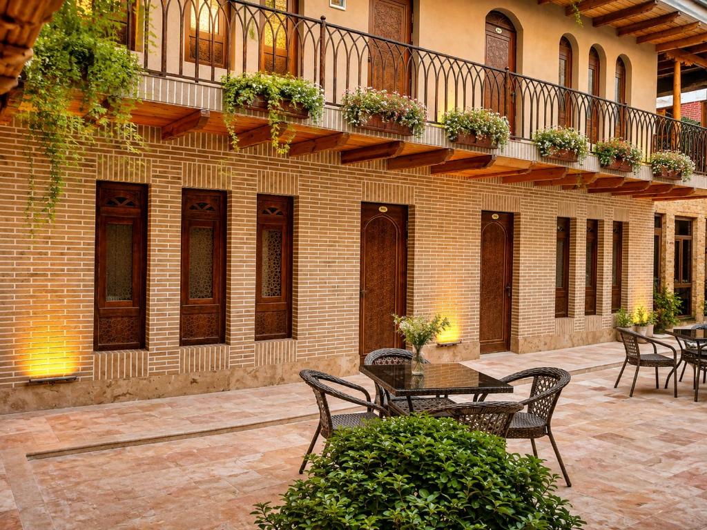 a patio with tables and chairs and a balcony at AYUB Modern & Heritage HOTEL in Bukhara