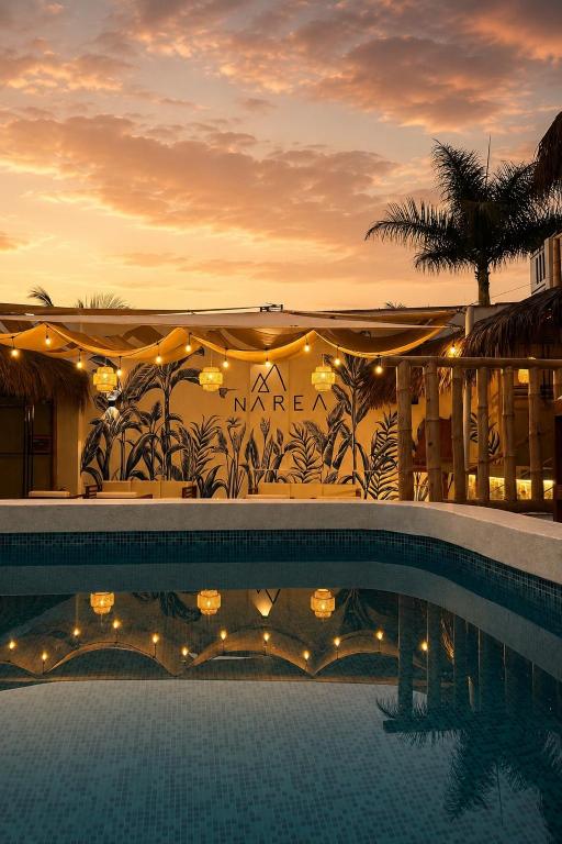 a resort with a swimming pool with a sunset in the background at Narea San Bartolo in San Bartolo