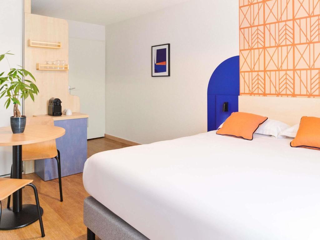 a bedroom with a large bed and a table at Aparthotel Adagio Access Rennes Centre in Rennes