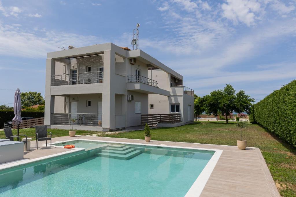 a villa with a swimming pool in front of a house at Marion Apartments in Kourouta