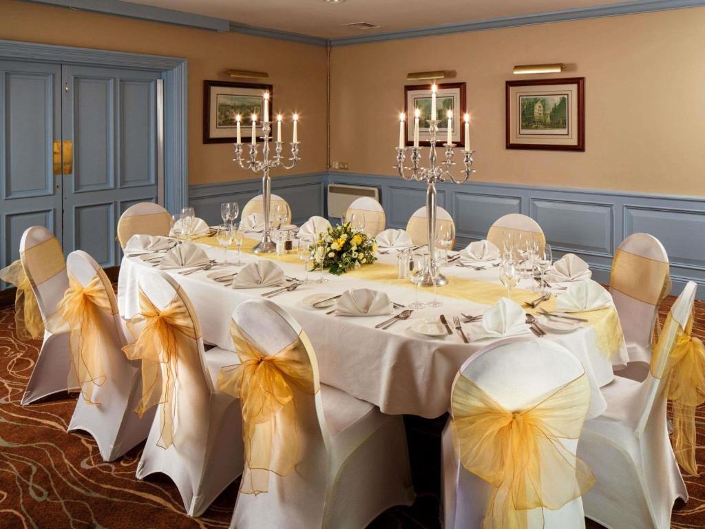 a banquet room with a long table with white tables and chairs at Mercure Livingston Hotel in Livingston