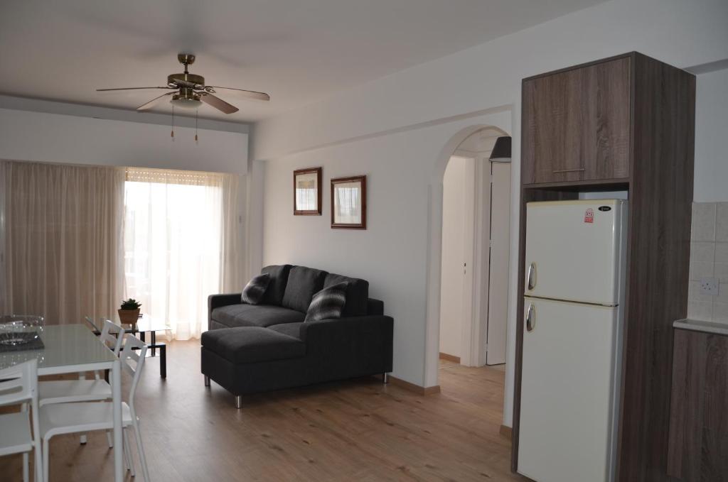 a living room with a black couch and a white refrigerator at Surf & Sun Holiday Apartments in Limassol