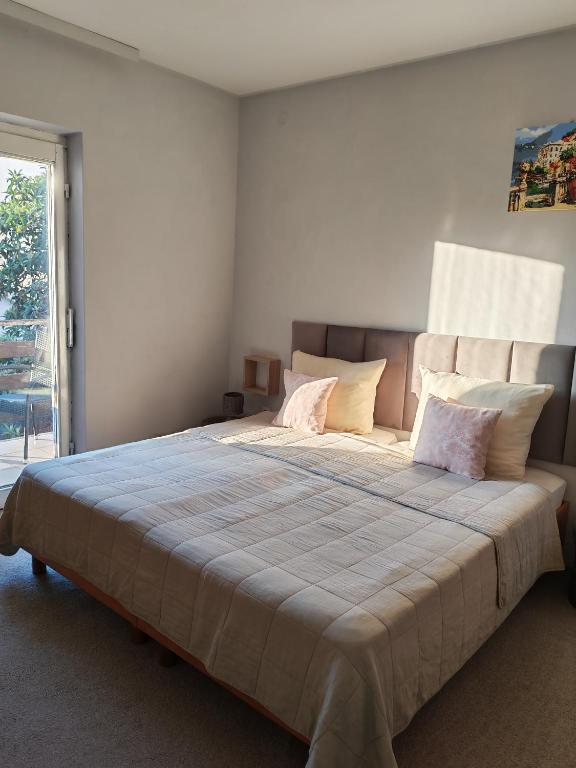 a bedroom with a large bed with pillows and a window at Apartmani Svitlana in Sukošan