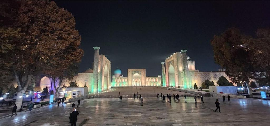a group of people walking around a building at night at Registan Stay in Samarkand