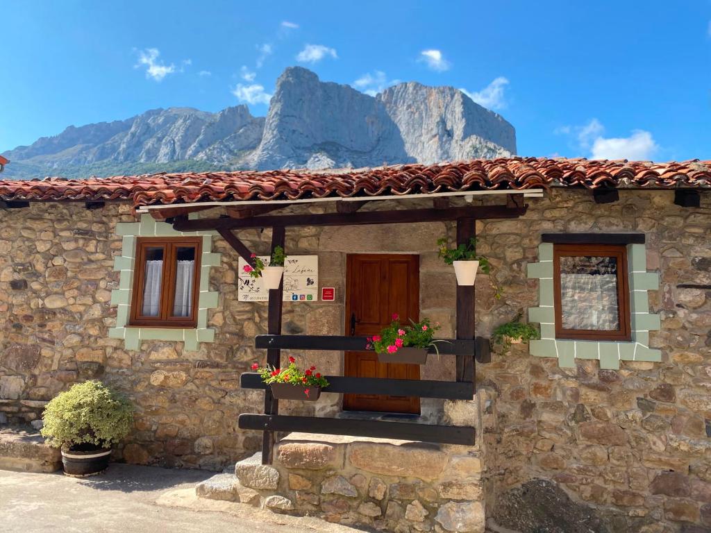 a stone house with flowers in front of a mountain at La Casuca ONE De Lebeña in Lebena