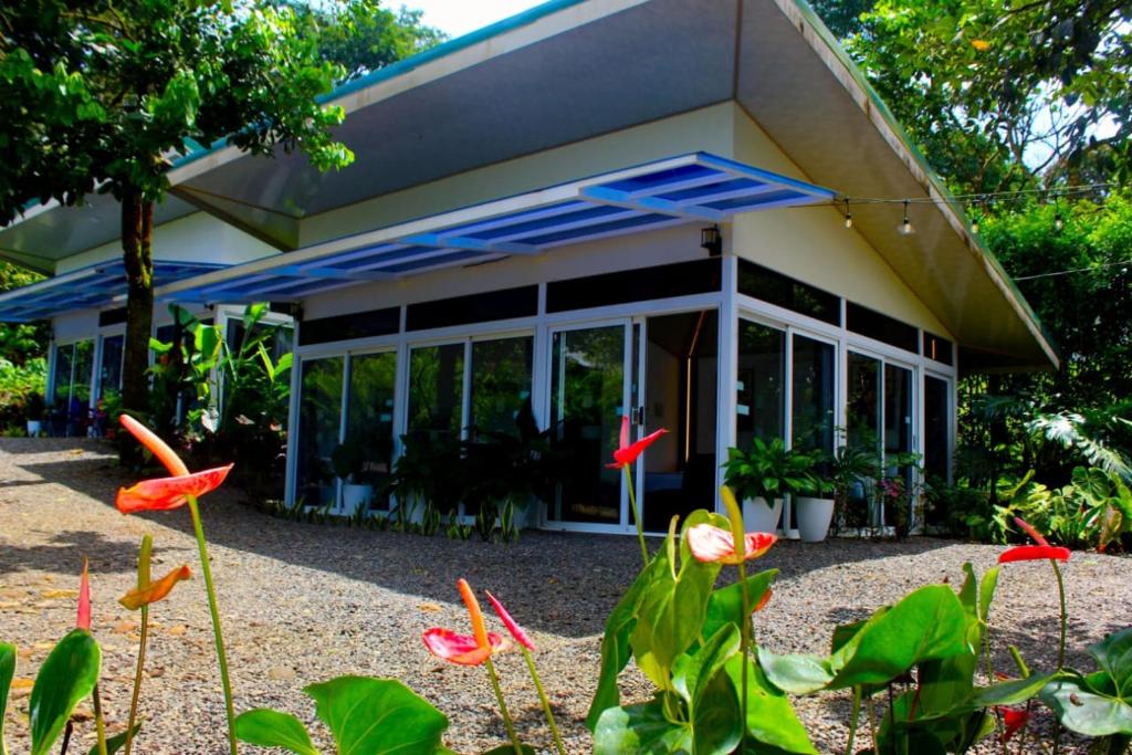 a house with a lot of windows and some flowers at Pino Lodge, Río Celeste in Bijagua