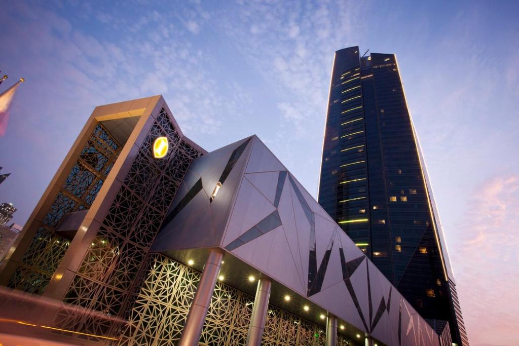 a large building with a clock on it with a tall building at InterContinental Doha The City by IHG in Doha