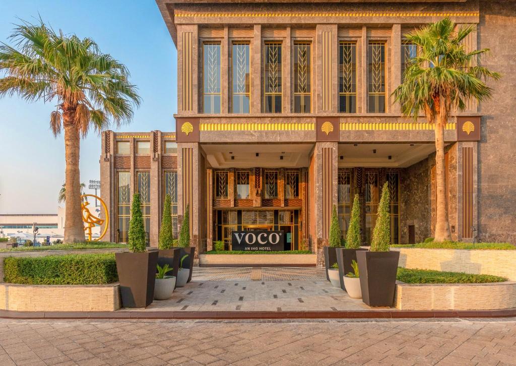 a building with palm trees in front of it at voco Doha West Bay Suites by IHG in Doha