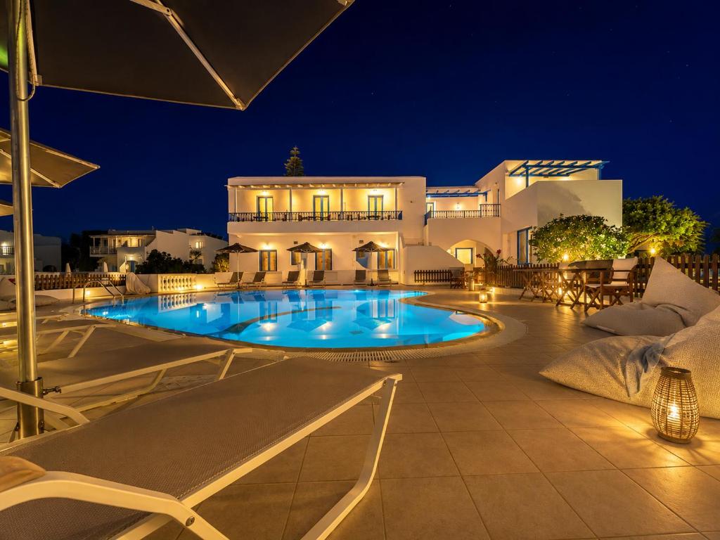 a swimming pool in front of a building at night at Anna Studios in Agios Prokopios