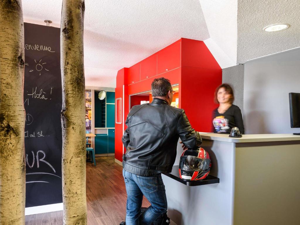a man standing at a counter in front of a woman at hotel F1 Vannes in Vannes