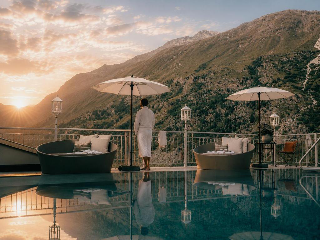 a man standing next to a pool at a resort at Hotel Bellevue - 4 Sterne superior in Obergurgl