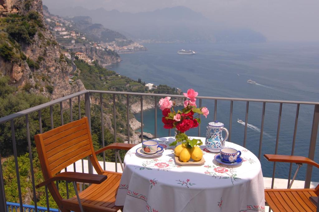a table with flowers and fruit on top of a balcony at Casa Marechiaro in Conca dei Marini