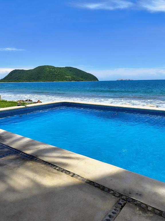 a large blue swimming pool next to the ocean at Tranquilidad Total Frente al Mar I 3 Hab y Alberca in Barra de Potosi