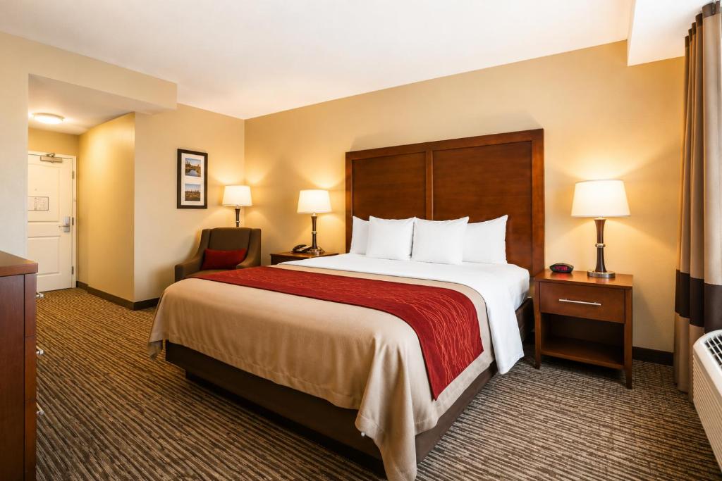 a hotel room with a large bed and a chair at Comfort Inn Pomona near Fairplex in Pomona