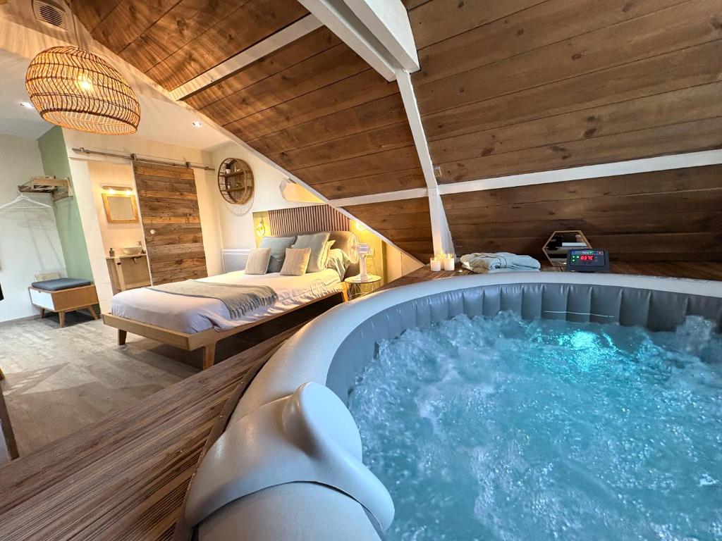 a large jacuzzi tub in a room with a bed at Escale en Avesnois in Croix-Caluyau