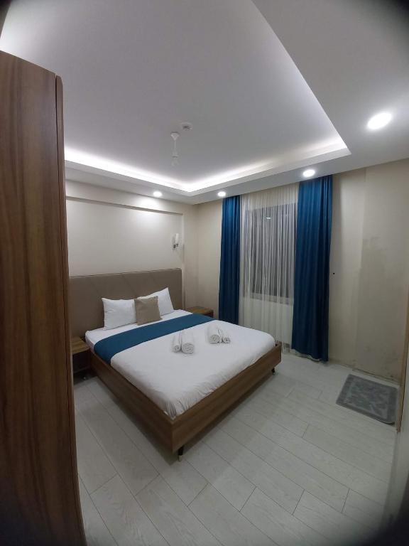 a bedroom with a large bed with blue curtains at Liva Teras Suites Uzungöl in Uzungöl