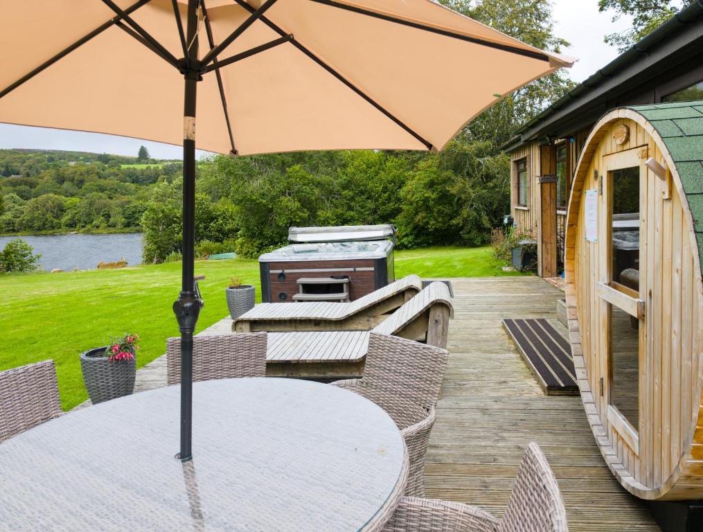 a table with an umbrella on a deck with a grill at Kinloch Lodge in Drumnadrochit