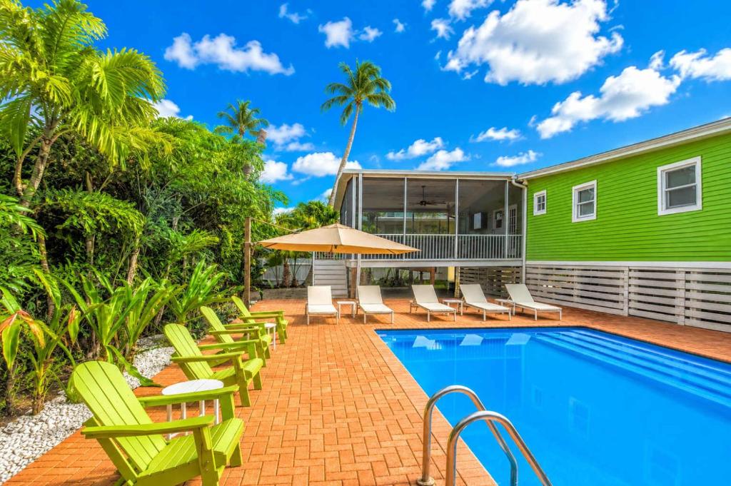 a swimming pool with chairs and a green building at 275 Ohio in Fort Myers Beach