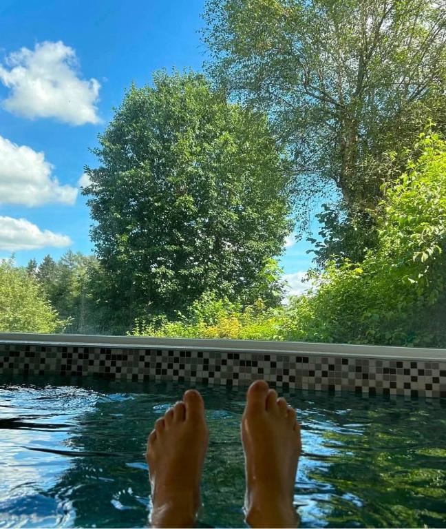 a person with their feet in a swimming pool at O'Calm - Gite A-2h wellness par nuitée à réserver in Jenneville