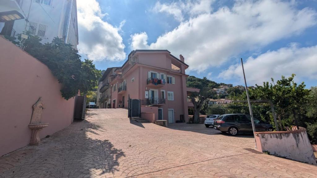 a street with a pink building on the side of a road at Grecale in Centola