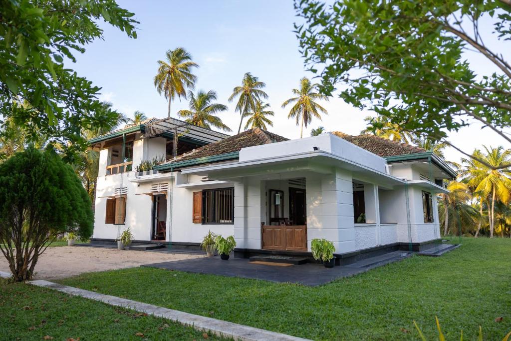 a white house with palm trees in the background at Don Padris Estate Bungalow in Tangalle