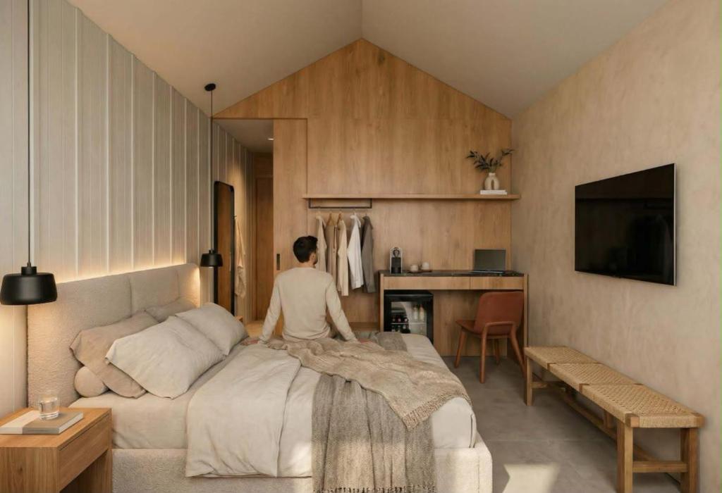 a man sitting on a bed in a bedroom at Apart Hotel Jardín in El Calafate