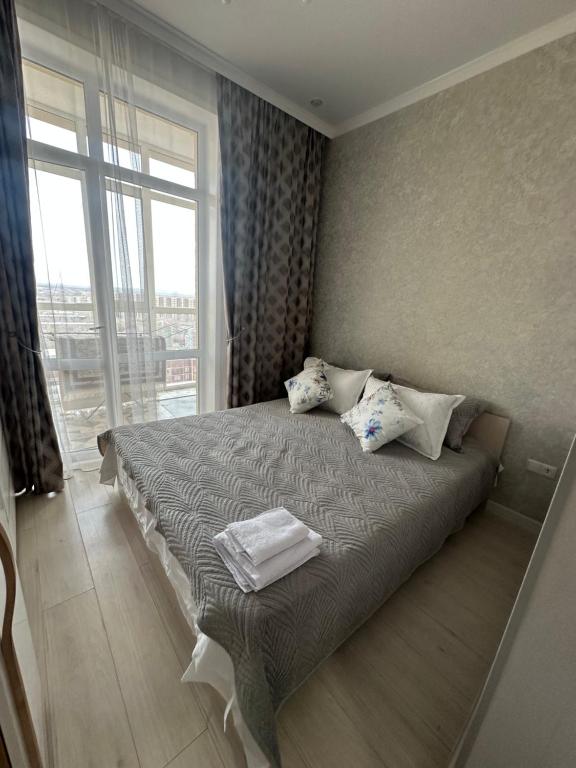 a bedroom with a bed with pillows and a window at Dostar Apartments in Karagandy