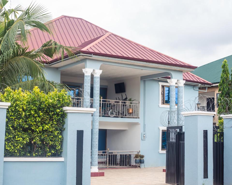 a blue house with a red roof at Big Papa Hotel in Amasaman