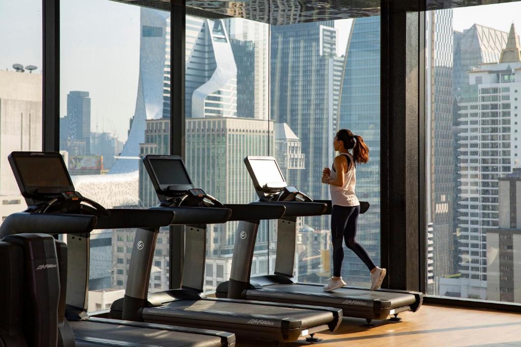 Treadmills face floor-to-ceiling windows over Bangkok’s high-rise skyline.