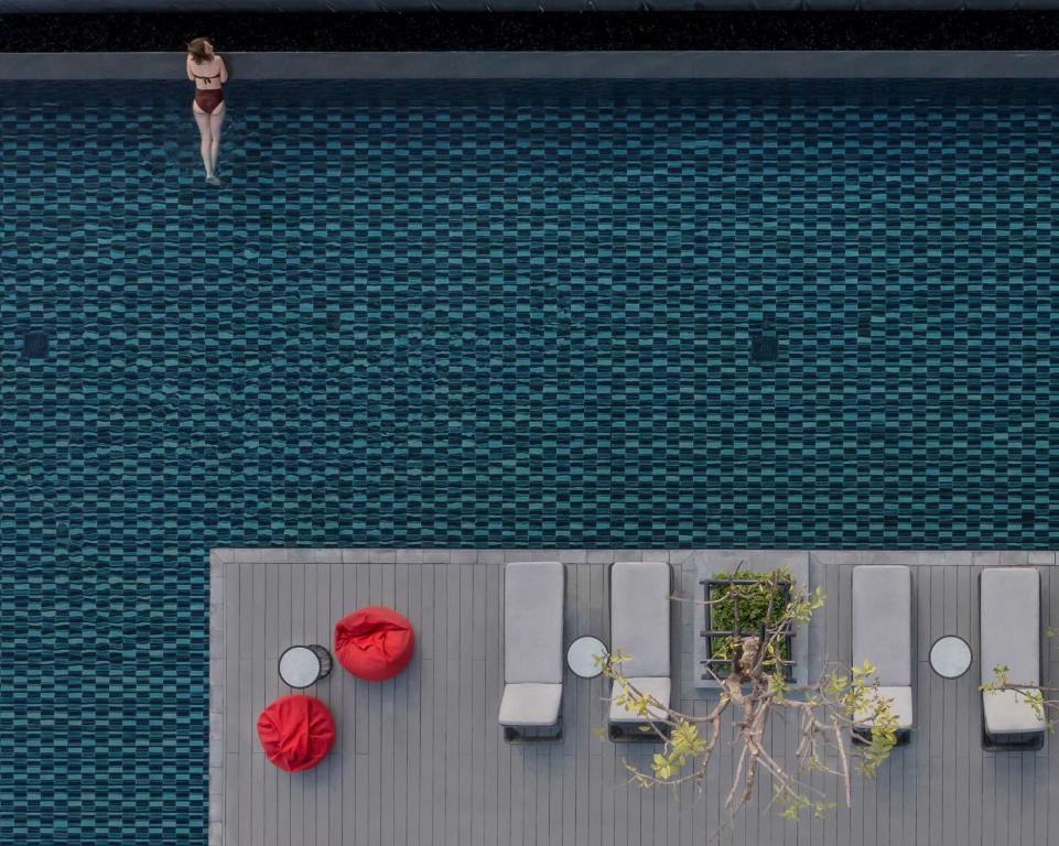 An overhead view of a rooftop pool with a narrow deck and scattered loungers.