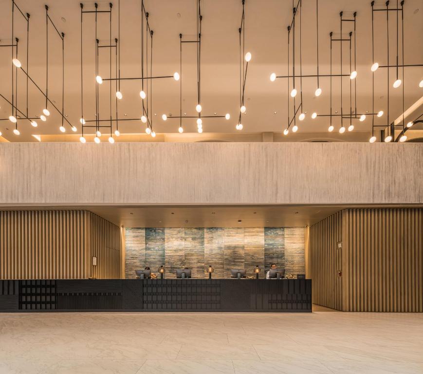 A spacious modern reception lobby with a long desk and warm pendant lighting.