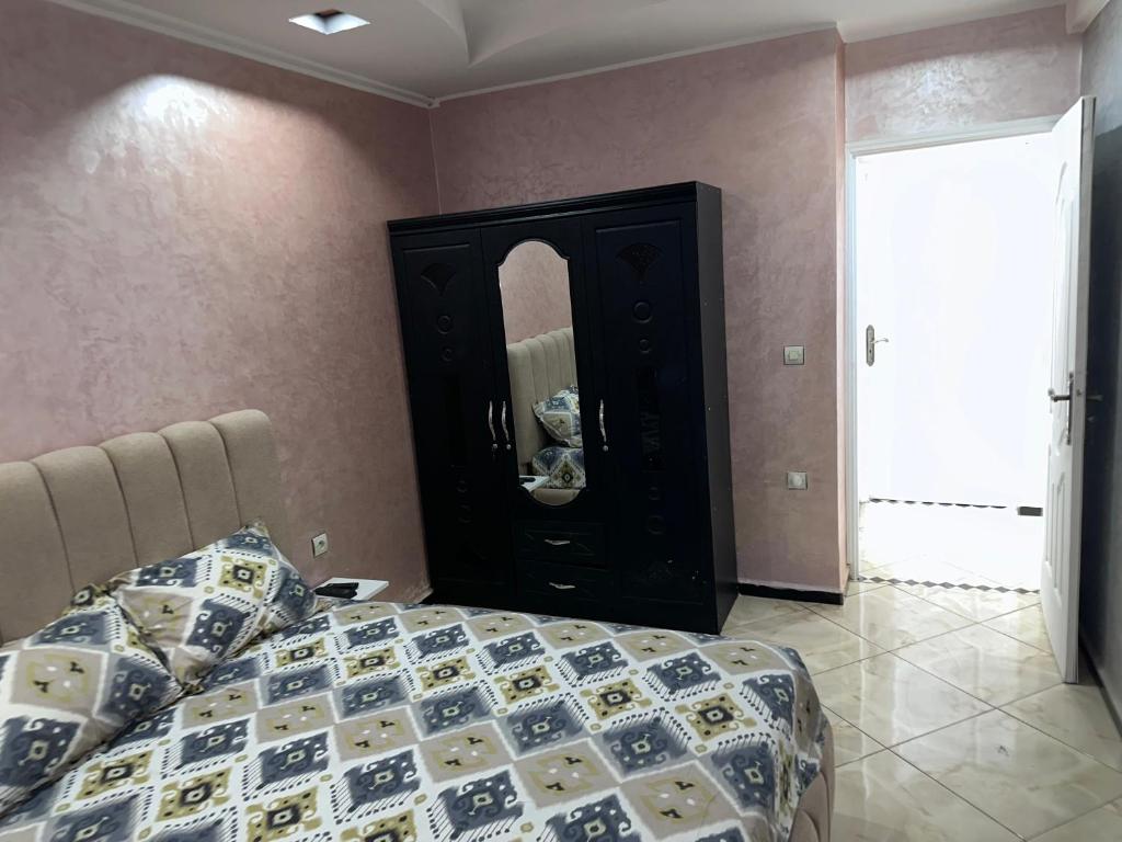a bedroom with a bed and a dresser with a mirror at Appartement in Khouribga